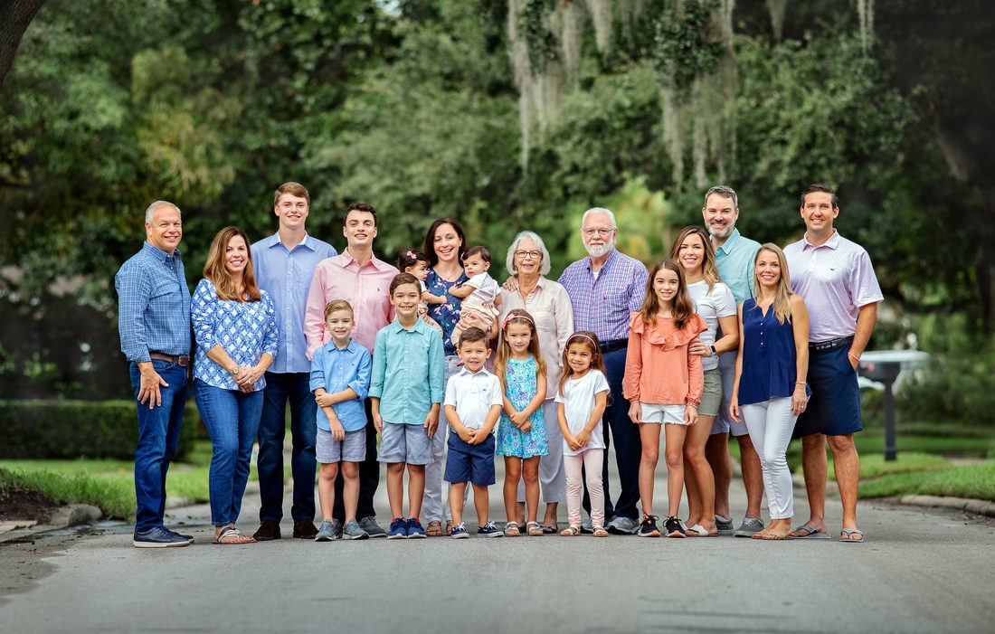 Large multi-generational family portrait on an oak-lined street