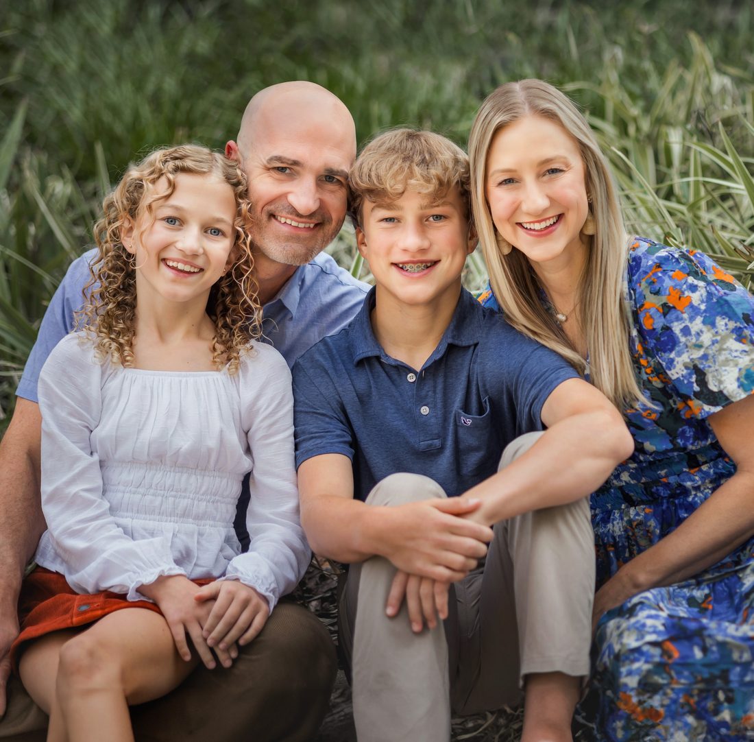 Family of four portrait sitting together outdoors