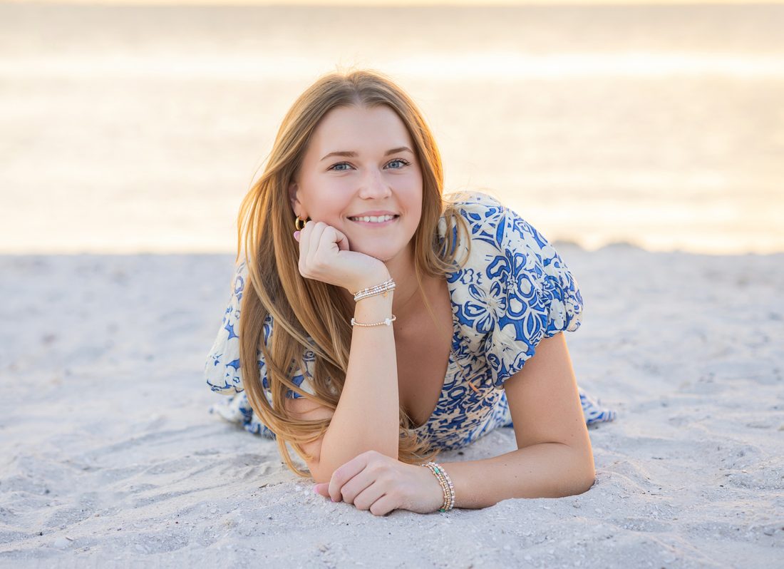 Senior portrait lying on the beach at golden hour