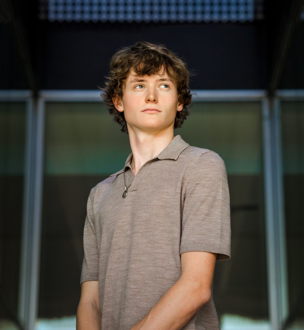 Senior portrait of a young man in front of a modern glass building