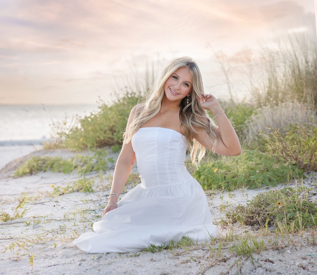 Senior portrait kneeling in the dunes at sunset